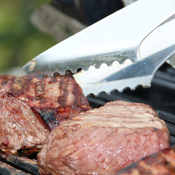 Grillzange wendet Grillfleisch