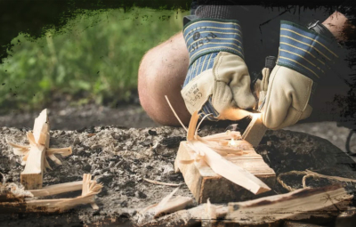 Bild zweier behandschuhter Hände, die ein Feuer entzünden